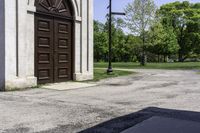 a man is standing next to a large church door near a green field and trees