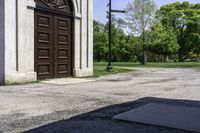 a man is standing next to a large church door near a green field and trees