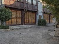 a statue in front of a large building with wooden panels on the side walk and large windows on the rear of the house