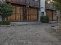 a statue in front of a large building with wooden panels on the side walk and large windows on the rear of the house