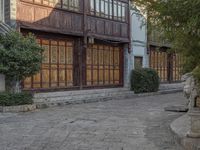 a statue in front of a large building with wooden panels on the side walk and large windows on the rear of the house