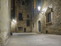 a dimly lit alleyway between old brick walls and concrete buildings with two windows, in an italian town