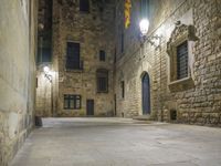 a dimly lit alleyway between old brick walls and concrete buildings with two windows, in an italian town