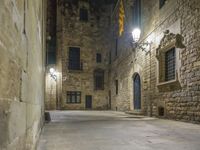 a dimly lit alleyway between old brick walls and concrete buildings with two windows, in an italian town