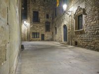 a dimly lit alleyway between old brick walls and concrete buildings with two windows, in an italian town