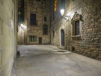 a dimly lit alleyway between old brick walls and concrete buildings with two windows, in an italian town