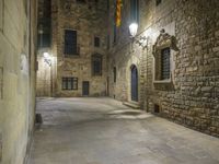 a dimly lit alleyway between old brick walls and concrete buildings with two windows, in an italian town