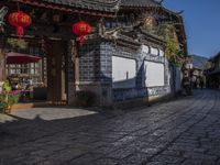 the street in a city has a long brick road and several houses with chinese architecture