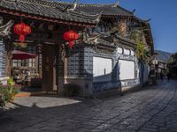 the street in a city has a long brick road and several houses with chinese architecture