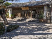 a small patio outside a building with trees in the foreground and plants growing around the door