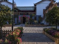 the entrance to an oriental house with a brick walkway and flower beds on either side