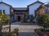 the entrance to an oriental house with a brick walkway and flower beds on either side