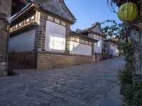 street view of old building with lanterns on top of bricked area, in chinese village