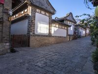 street view of old building with lanterns on top of bricked area, in chinese village