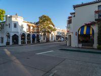 a row of buildings and a small white car on a street corner in the sunlight