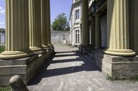 a stone walkway leading to some ancient buildings, with several pillars that are standing alone