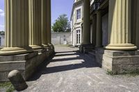 a stone walkway leading to some ancient buildings, with several pillars that are standing alone