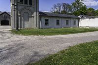 the view of a small church through a driveway by a lawn with a fire hydrant