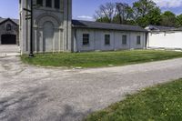 the view of a small church through a driveway by a lawn with a fire hydrant