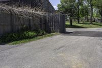 a parking lot with a fence and two barns in the background and trees in the foreground