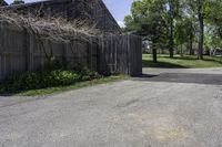 a parking lot with a fence and two barns in the background and trees in the foreground