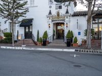 white house with lights on side and stairs in front with pots with plants outside of it