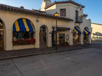 the streets are empty and blue, with yellow awnings and flower boxes on each corner