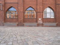 a brick courtyard with windows and benches on the ground, near it is an old building