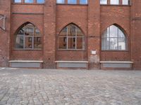 a brick courtyard with windows and benches on the ground, near it is an old building