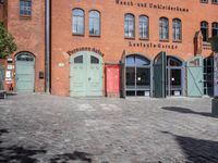 a cobblestone street with red and green doors leading to the entrance of an historic building