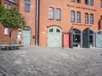 a cobblestone street with red and green doors leading to the entrance of an historic building