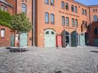 a cobblestone street with red and green doors leading to the entrance of an historic building