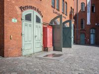 a cobblestone street with red and green doors leading to the entrance of an historic building