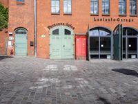 a cobblestone street with red and green doors leading to the entrance of an historic building