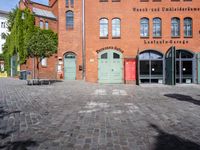 a cobblestone street with red and green doors leading to the entrance of an historic building