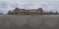 a view of a large building from the sidewalk in a panorama camera mode that looks like a reflection of it on a mirror