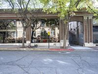 the view of a very old style building from the street corner that has a row of trees in front of it