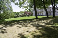 an exterior view of a large house sitting among trees and grass in a park,