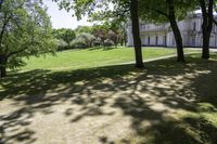 an exterior view of a large house sitting among trees and grass in a park,