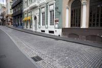 the sidewalk on the ground is made from small pieces of cobblestones with a window and lamp posts