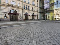 people walking on sidewalk in front of an old hotel building with large windows and doors