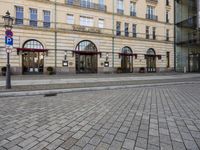 people walking on sidewalk in front of an old hotel building with large windows and doors