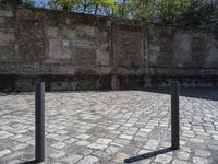 an empty courtyard has bricks lining it with green trees in the background and a brick wall