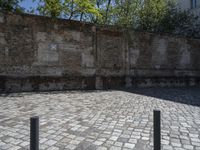 an empty courtyard has bricks lining it with green trees in the background and a brick wall