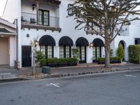 a house with an overhang that is next to a tree and street in front