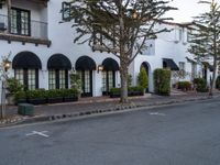 a house with an overhang that is next to a tree and street in front