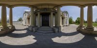 there are columns near a front door in the large house structure in the foreground