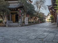 a long street with many buildings and trees on it's sides with red lanterns