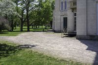 a bike parked in front of an old mansion building on the grass in front of it is an empty path