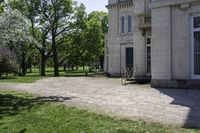 a bike parked in front of an old mansion building on the grass in front of it is an empty path